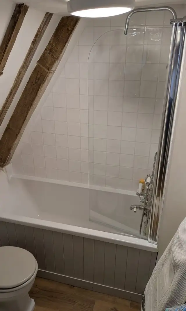 White bath and shower screen under exposed timber beams