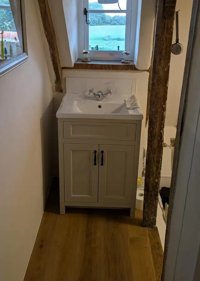 Cream vanity unit with traditional taps under a cottage window